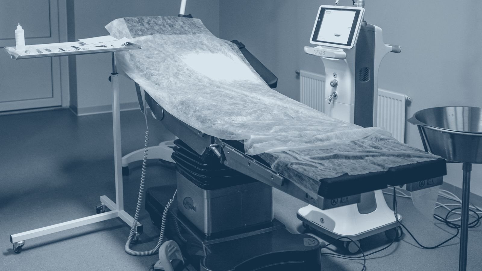 An operating theatre prepared for a case, with table, instrument tray and monitor