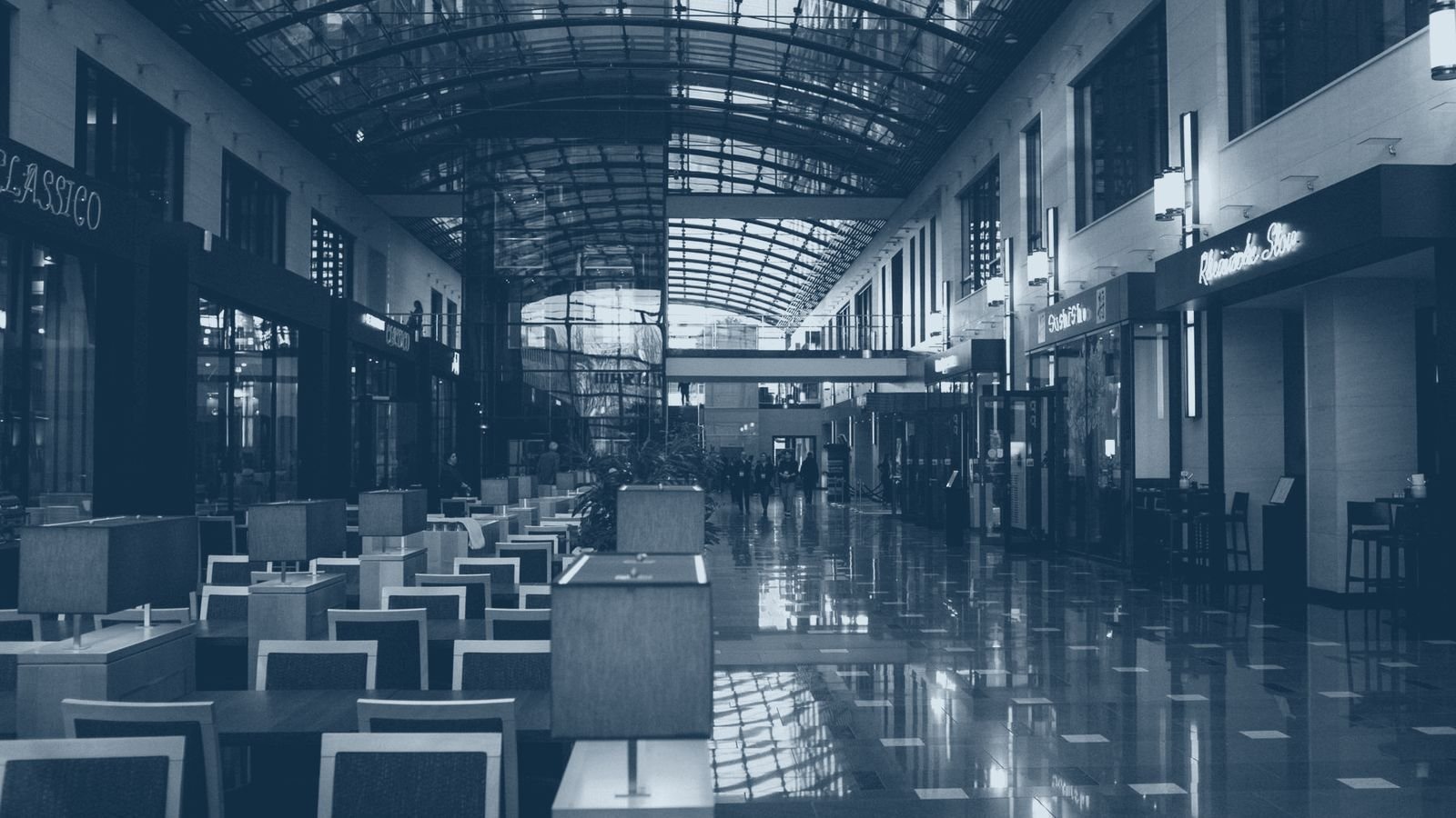 The concourse of a modern shopping centre under a glazed roof