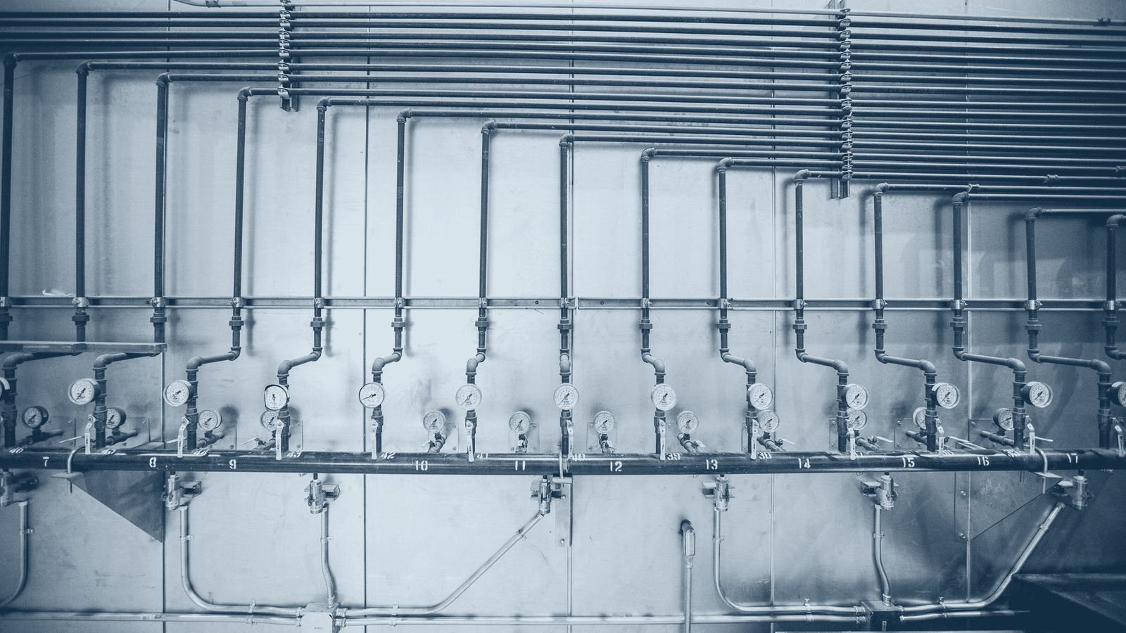 Industrial pressure gauges and steel pipework on a plant wall