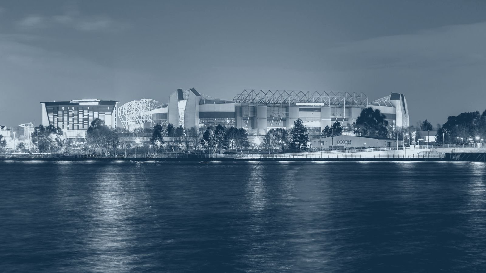 A floodlit stadium reflected in water at night