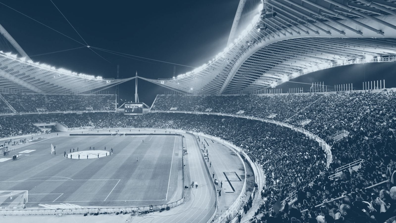 A full stadium crowd under floodlights during an evening fixture